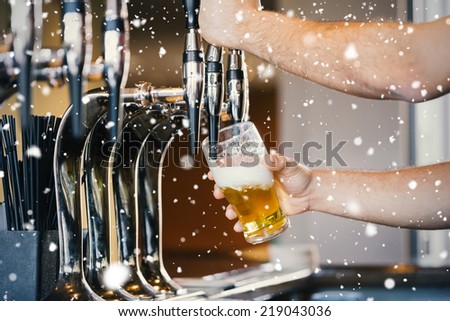 Composite image of Barmans arms pulling a pint of beer against snow falling