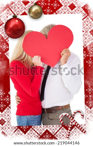 Handsome man getting a heart card form wife against christmas themed page