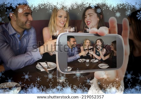 Hand holding smartphone showing against snow flake frame in blue