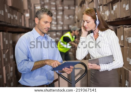 Warehouse manager and foreman working together in a large warehouse