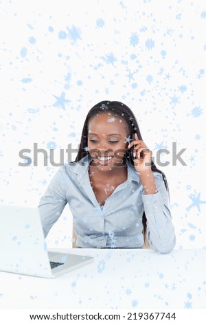 Composite image of Portrait of a businesswoman making a phone call while using a laptop with snow falling