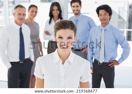 Business woman smiling at camera with co-workers behind her