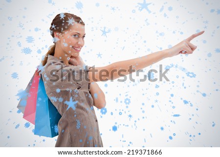 Side view of pointing woman with shopping bags against snow falling