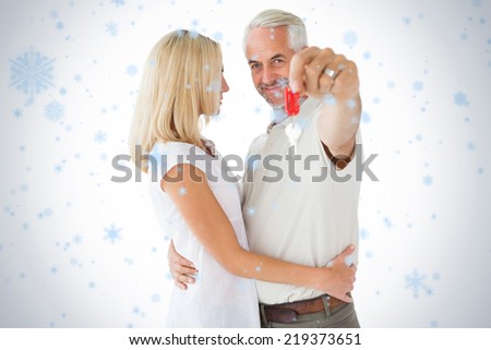 Happy couple showing their new house key against snow falling