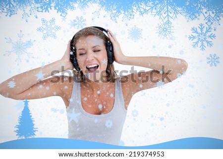 Happy woman singing while listening to music against snow flake frame in blue