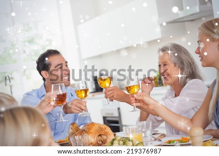 Family raising their glasses at thanksgiving dinner against snow falling