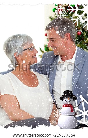 Composite image of a Senior couple in love in Christmas against snow falling