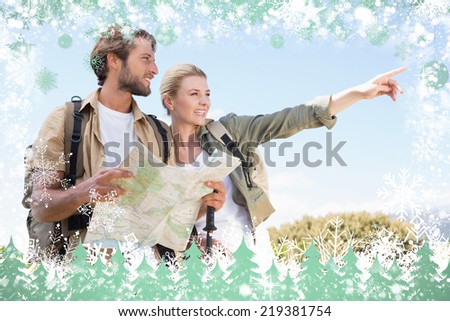 Attractive hiking couple reading the map on mountain trail against snow