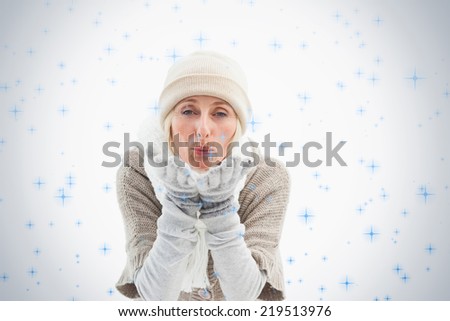 Mature woman in winter clothes blowing kiss against twinkling stars