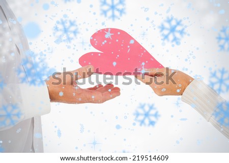 Woman handing man a paper heart against snowflakes