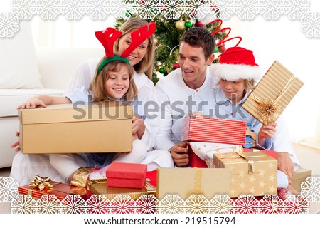 Young family having fun with Christmas gifts against snowflake frame
