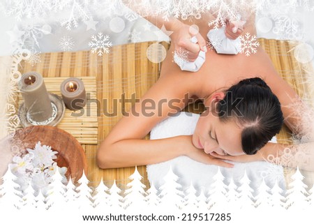 Peaceful brunette enjoying a herbal compress massage against fir tree forest and snowflakes