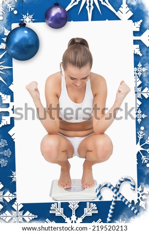 Successful young woman crouching on a scales against christmas frame