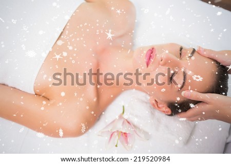 Attractive woman receiving head massage at spa center against snow falling