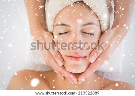 Attractive woman receiving facial massage at spa center against snow falling