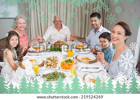 Portrait of an extended family at dining table against snowflakes and fir trees in green