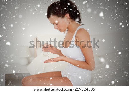 Composite image of sick woman taking pills against snow falling