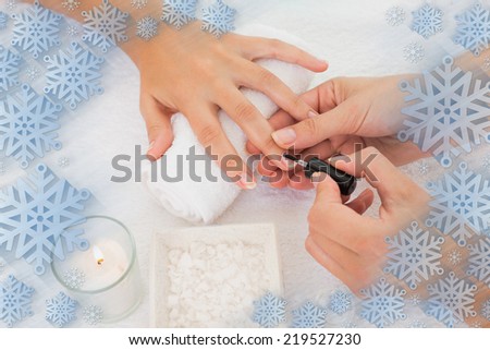Nail technician painting customers nails against snowflake frame