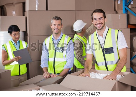 Warehouse workers in yellow vests preparing a shipment in a large warehouse