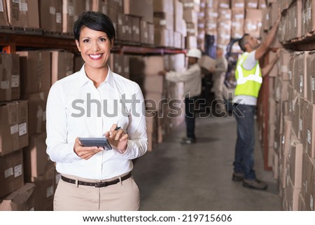 Pretty warehouse manager using calculator in a large warehouse