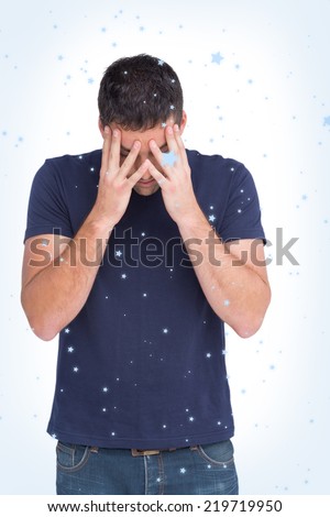 Upset man standing with his head in hands against snow falling