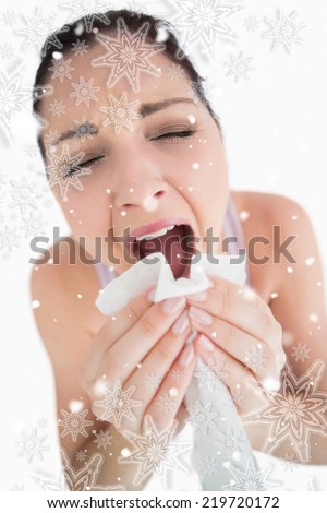 Woman sneezing into a tissue against snowflakes