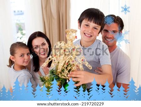 Happy little boy decorating a Christmas tree with his family against snowflakes and fir trees in blue