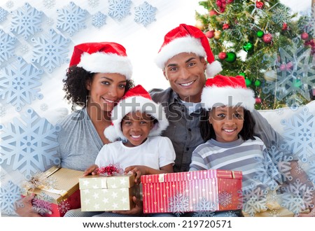 Composite image of family holding Christmas presents against snowflake frame
