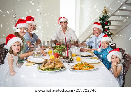 Composite image of Happy family in Santa hats having Christmas meal against snow falling