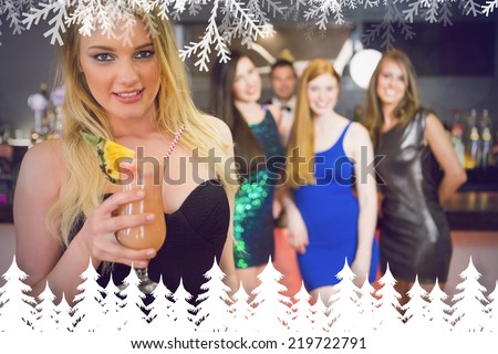 Blonde attractive woman holding cocktail standing in front of her friends against fir tree forest and snowflakes