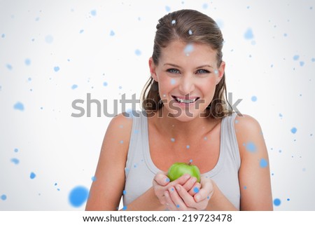 Smiling woman holding an apple against snow falling