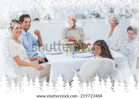 Family smiling at the dinner table against fir tree forest and snowflakes