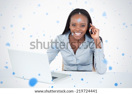 Businesswoman making a phone call while using a laptop against snow falling