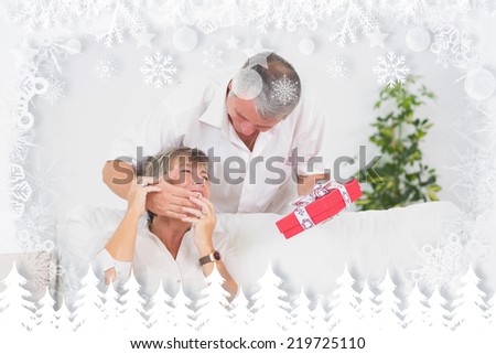 Old man hiding eyes his wife to give a gift against fir tree forest and snowflakes
