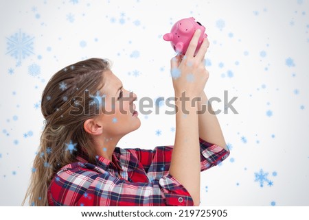 Woman looking inside a piggy bank against snow falling