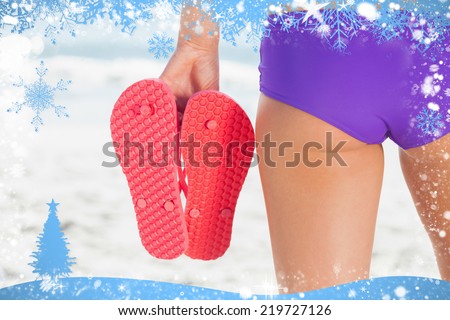 Composite image of snow frame against rear view of a young woman holding flip flops