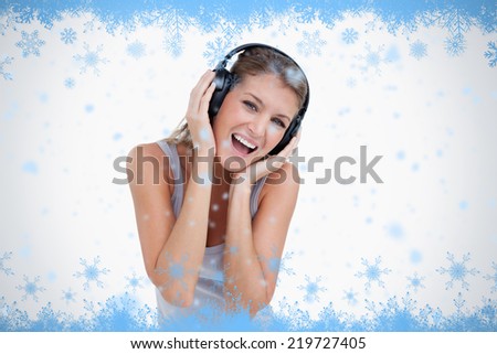 Woman singing while listening to music against snow flake frame in blue
