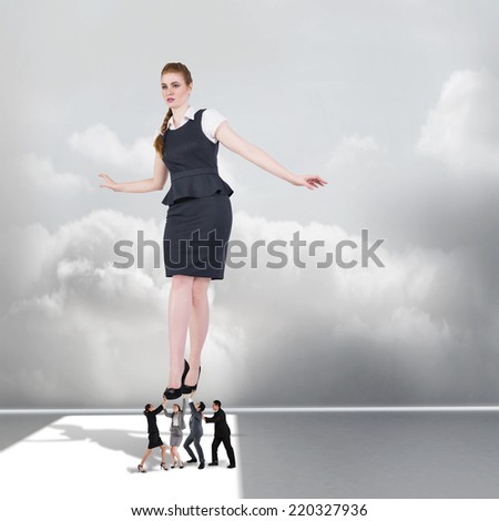 Composite image of business team supporting boss against clouds in a room