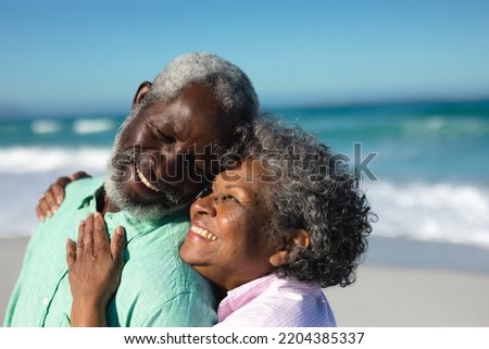 Side view close up of a senior African American couple standing on the beach with blue sky and sea in the background, embracing and smiling at each other Foto stock © 