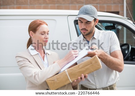 Delivery driver handing parcel to customer outside van outside the warehouse