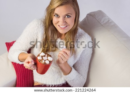 Pretty blonde enjoying hot chocolate on the couch at home in the living room