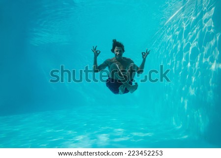 Full length portrait of a young man swimming underwater