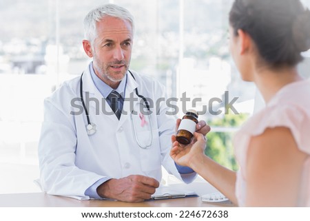 Patient holding jar of medicine wearing breast cancer awareness ribbon