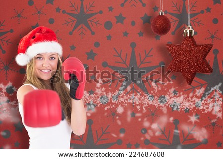 Festive blonde punching with boxing gloves against snowflake wallpaper pattern