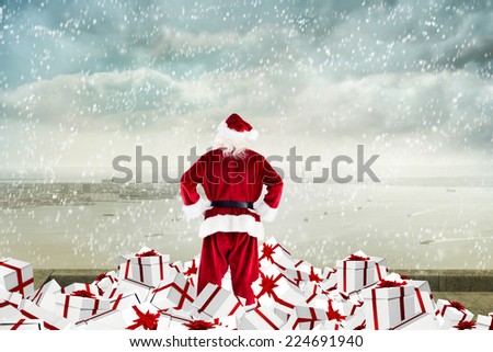 Santa standing on pile of gifts against coastline city