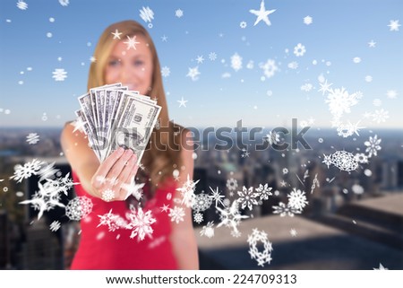 Pretty blonde showing wad of cash against city skyline