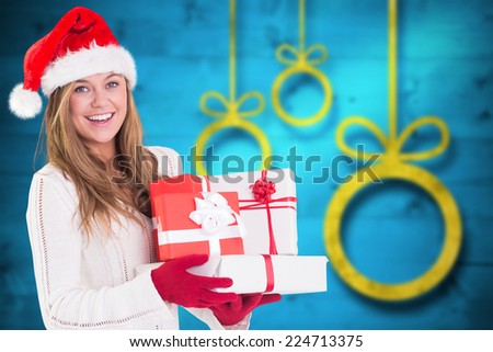 Festive blonde holding pile of gifts against blurred christmas background