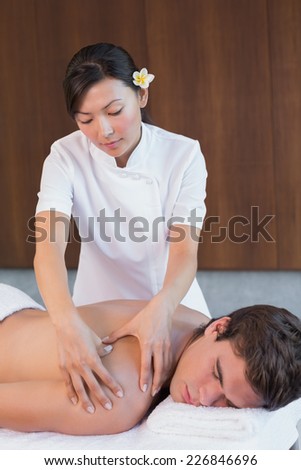 Portrait of a female masseur massaging man\'s back at spa center