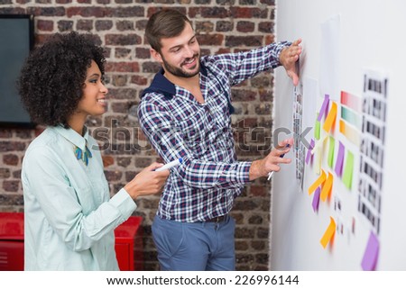 Creative business team looking at sticky notes on wall
