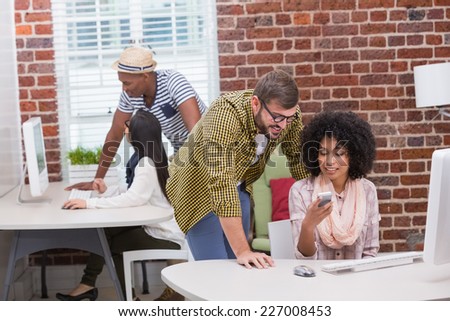 Creative business people looking at mobile phone at office